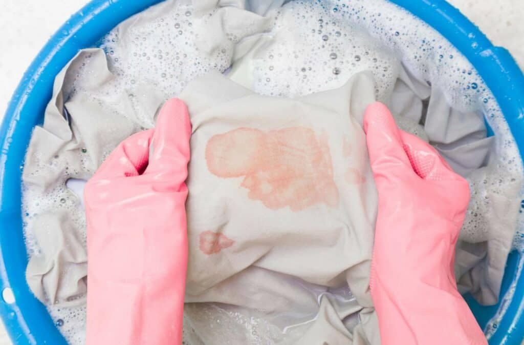 Hands in rubber protective gloves washing sheet with blood stains