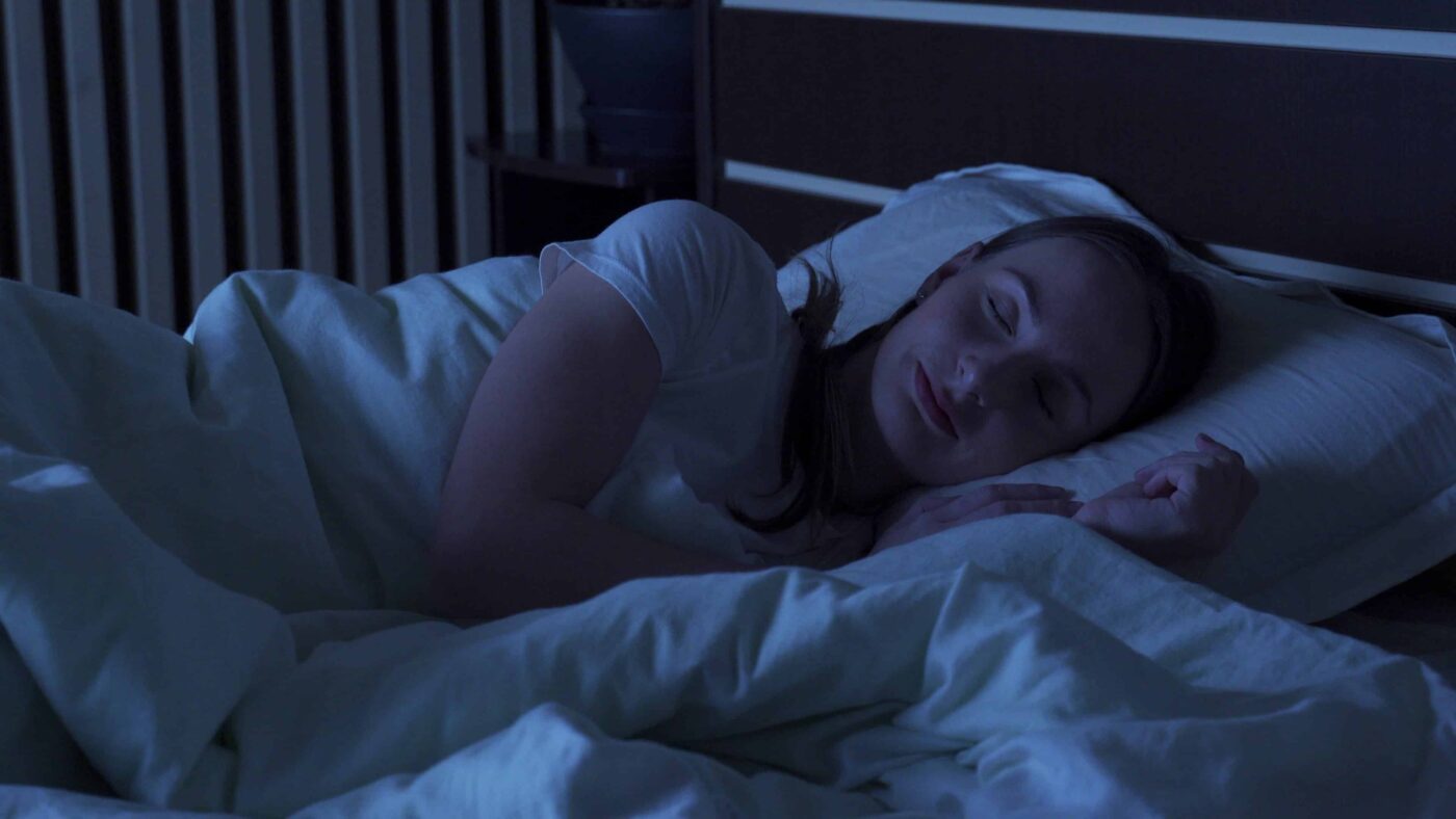 Young woman comfortably sleeping at night in a bed at home
