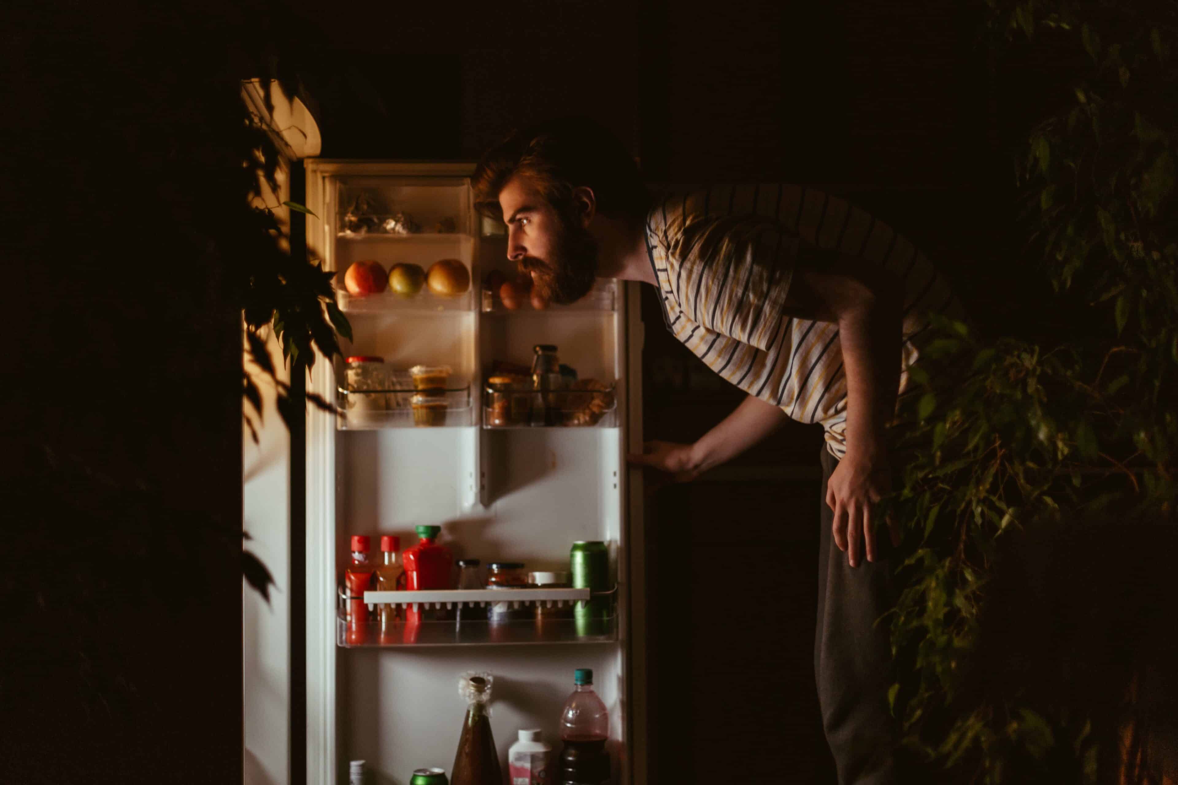 Man looking for healthy late-night snacks in the refrigerator late night